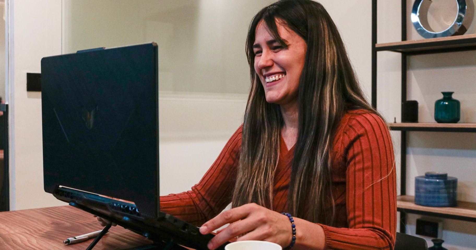 Profesional sonriendo durante una videollamada en su despacho